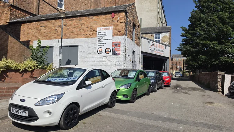 The L.A Motors sign above Pavilion Garage on Somerset Terrace, Scarborough, with used cars parked outside